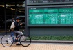 FILE PHOTO: A man on a bicycle stands in front of an electronic board showing Shanghai stock index, Nikkei share price index and  Dow Jones Industrial Average outside a brokerage in Tokyo, Japan September 22, 2022. REUTERS/Kim Kyung-Hoon