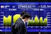 FILE PHOTO: Passersby walk past an electric monitor displaying Japan's Nikkei share average and recent movements outside a bank in Tokyo, Japan, March 22, 2023. REUTERS/Issei Kato