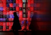 FILE PHOTO: A visitor walks past Japan's Nikkei stock prices quotation board inside a building in Tokyo, Japan February 19, 2024. REUTERS/Issei Kato/File Photo